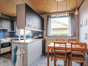 A modern kitchen with a central island, wooden ceiling, and pendant lighting.