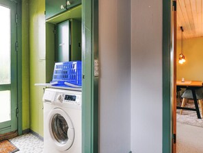 A laundry area with a washing machine and a blue basket on a shelf.