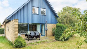 A blue house with a brick foundation, a covered outdoor seating area, and a garden. - 6 Person Holiday Home in Stokkemarke (Stokkemarke)