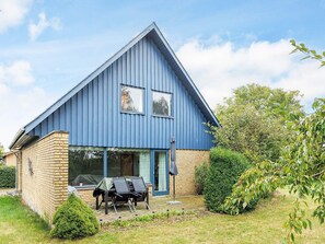 A blue house with a brick foundation, a covered outdoor seating area, and a garden. - 6 Person Holiday Home in Stokkemarke (Stokkemarke)