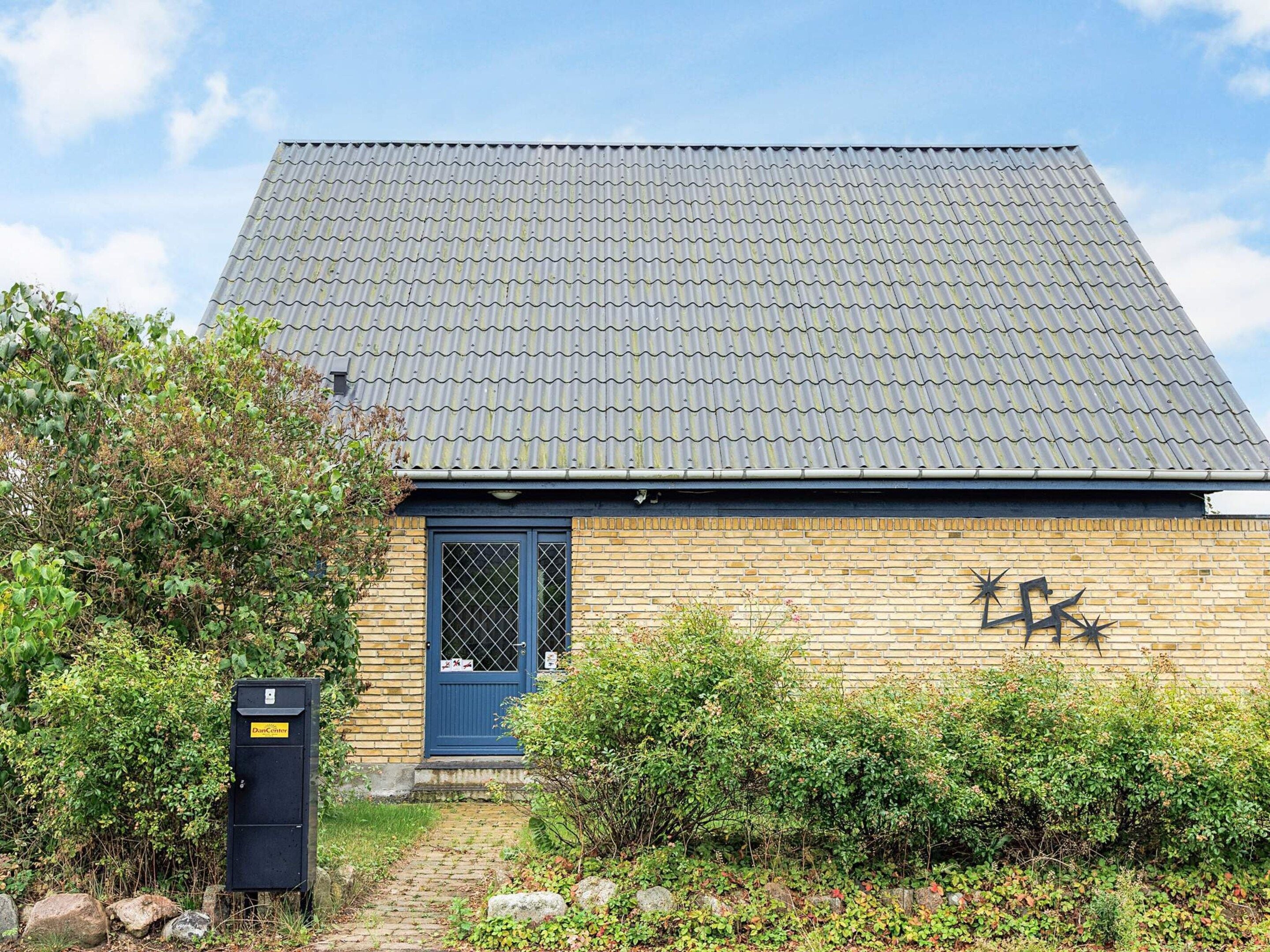Een gebouw met een pannendak, een blauwe deur en een bakstenen muur.