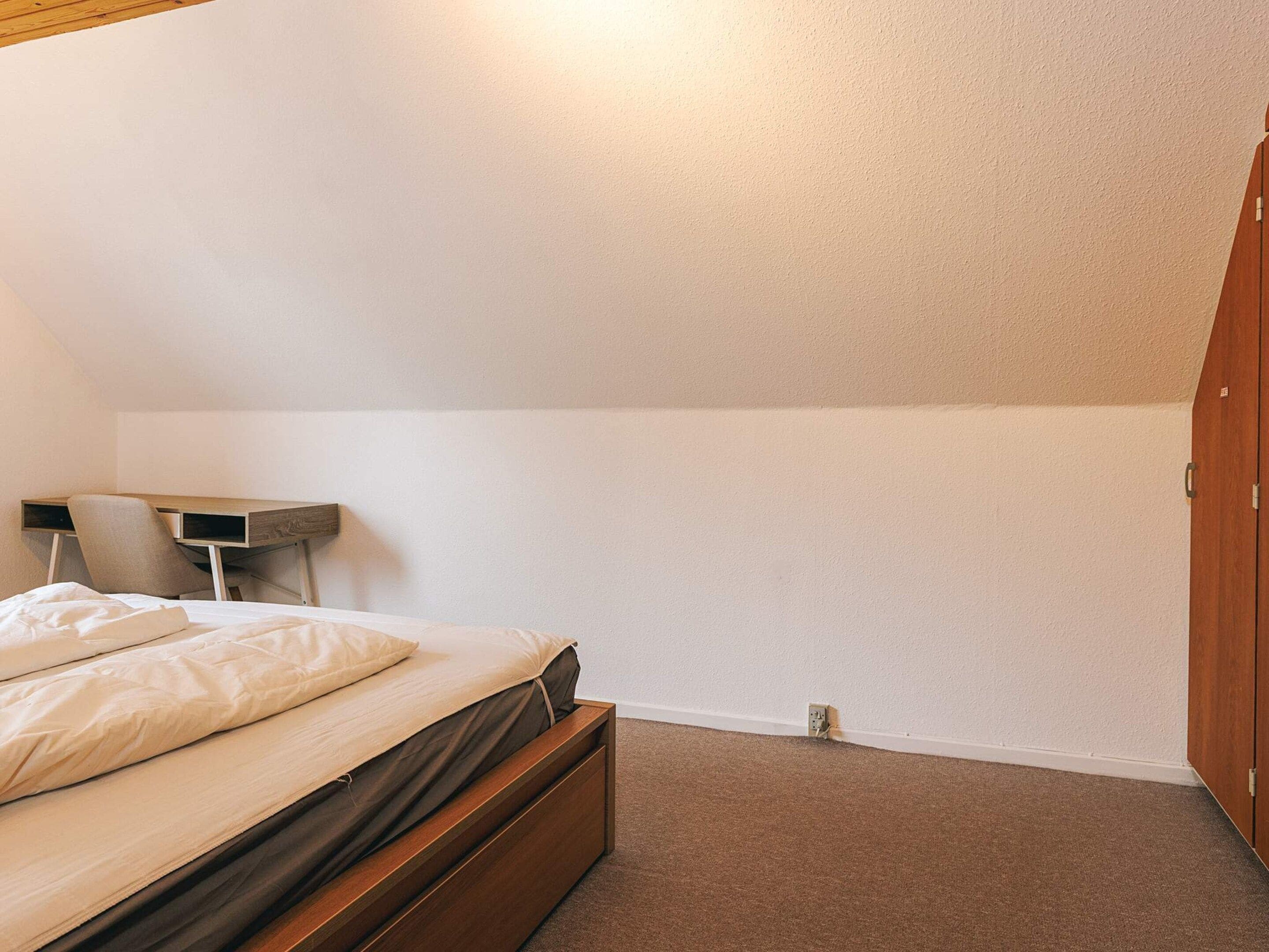 Une chambre à coucher avec un lit, un bureau et une armoire.