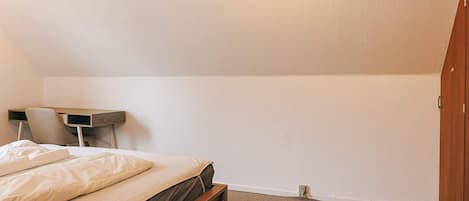 Un dormitorio con cama, escritorio y armario.