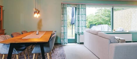 Un coin repas avec une table et des chaises en bois, un canapé et une fenêtre avec des rideaux.