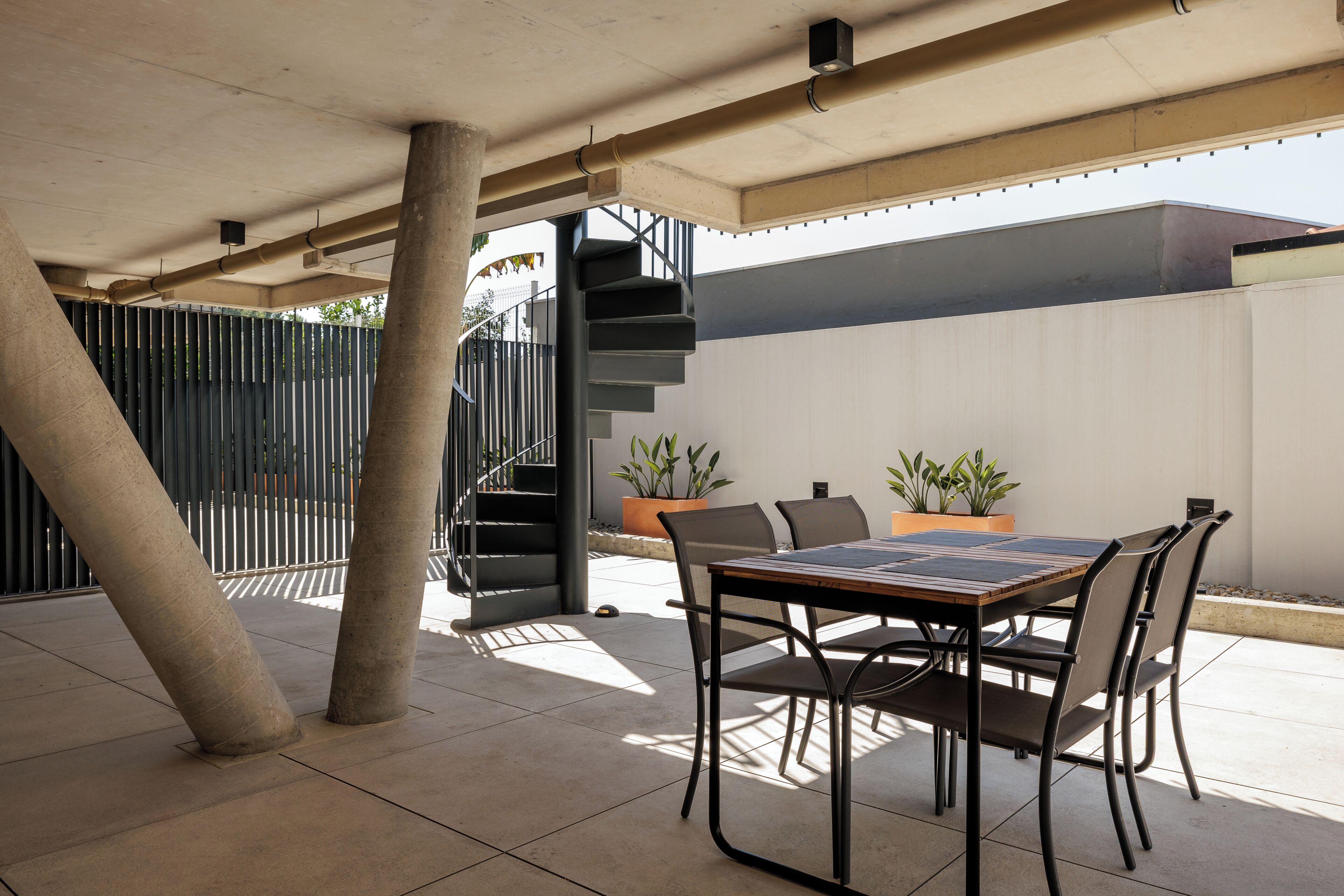 An outdoor patio with a table and chairs, a staircase, and potted plants.