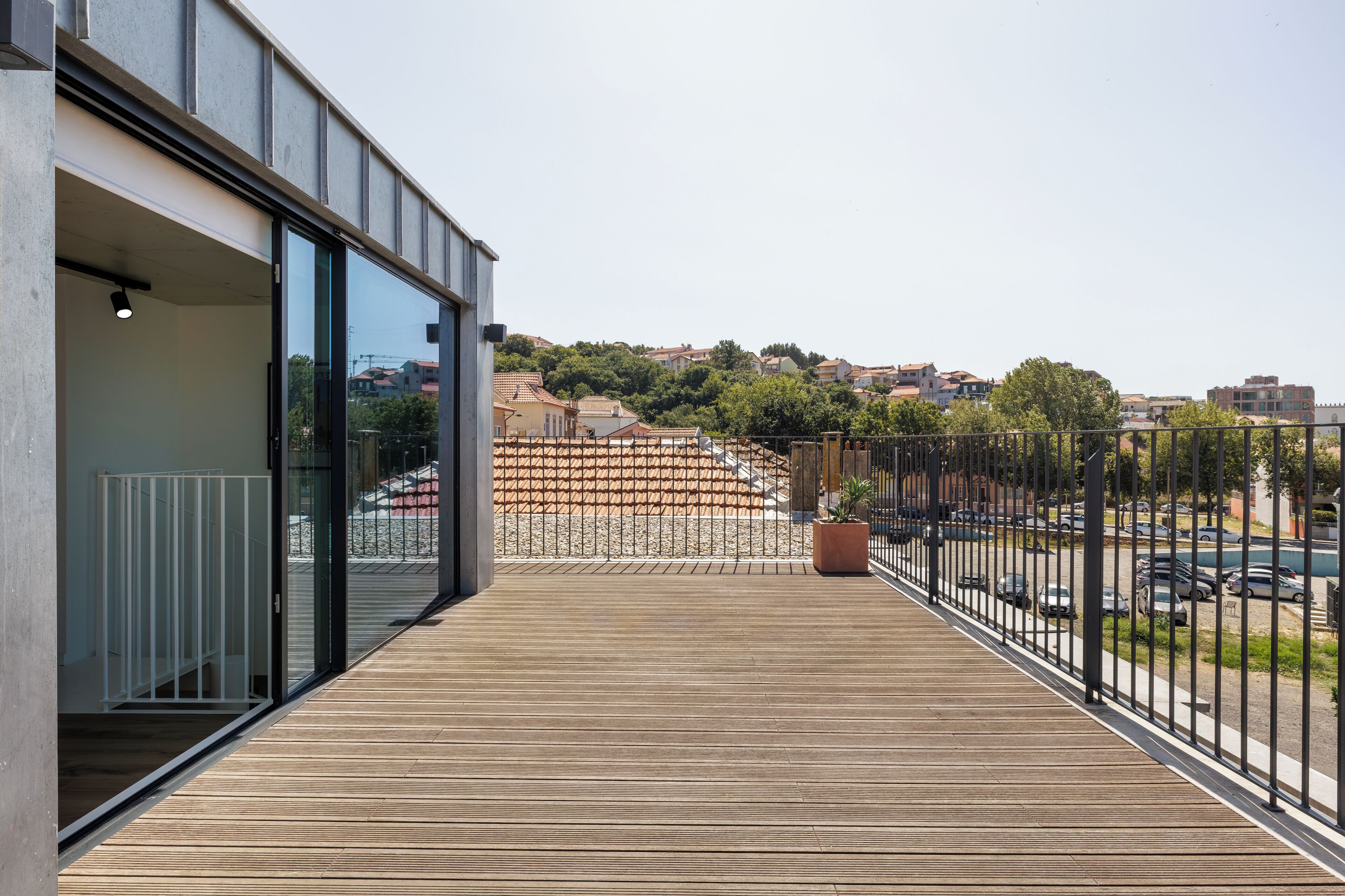 A balcony with a view of a parking area and buildings in the distance.