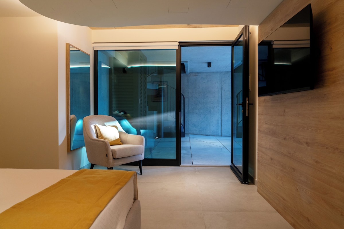 A modern bedroom with a bed, a chair, and a television.