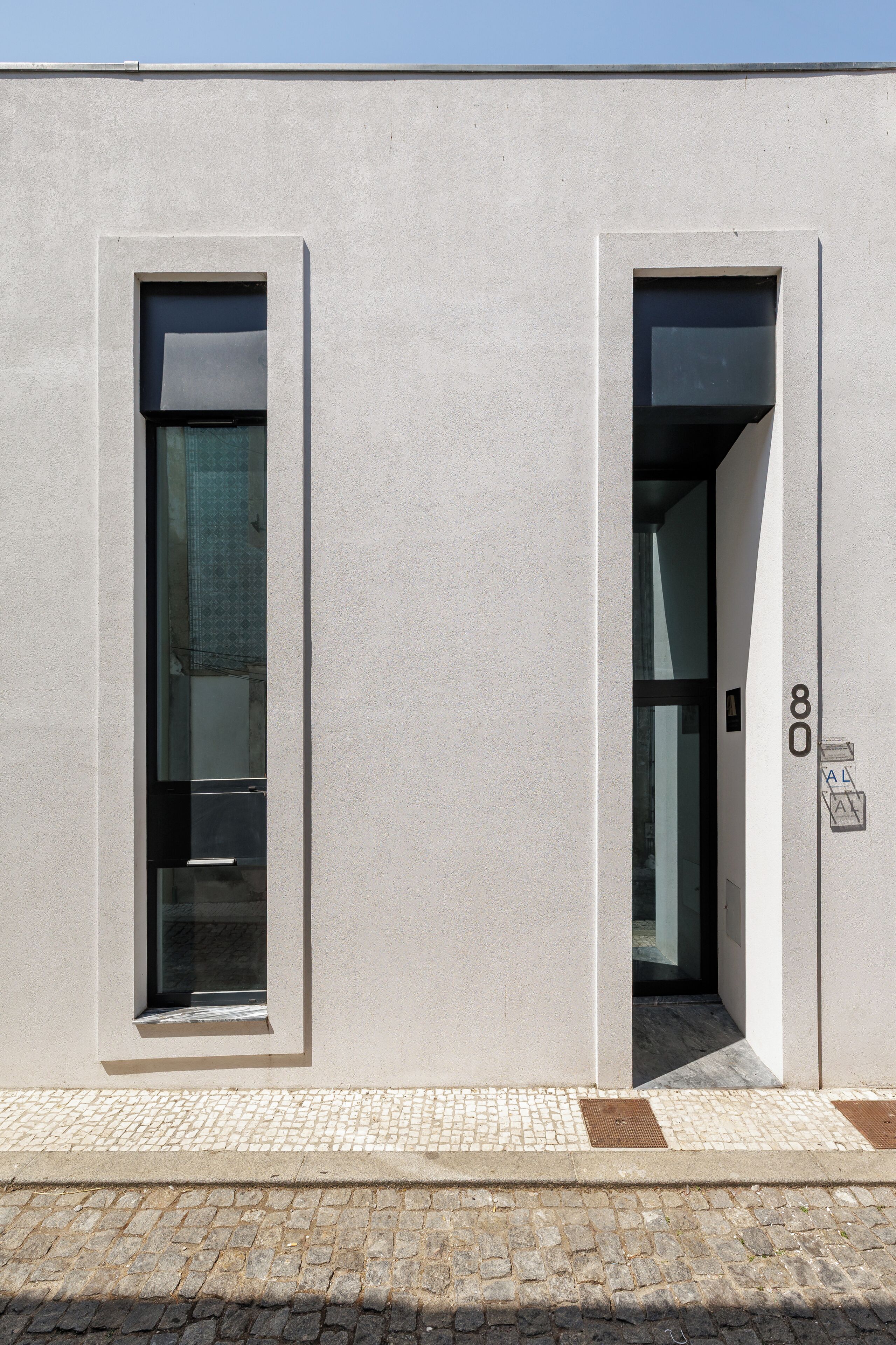 A building facade with two doors and a window, number 80 visible on the right door.