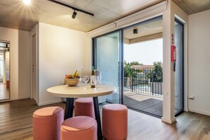 A modern interior with a round table, two stools, a bowl of fruit, and two wine glasses. - Marina da Afurada Apartments (Vila Nova de Gaia)