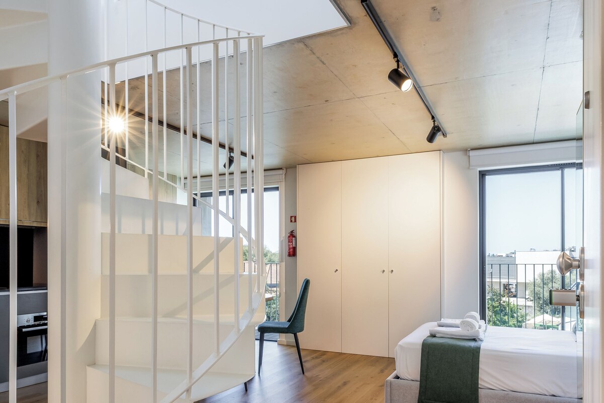A modern interior with a staircase, a bed, and a view through large windows.