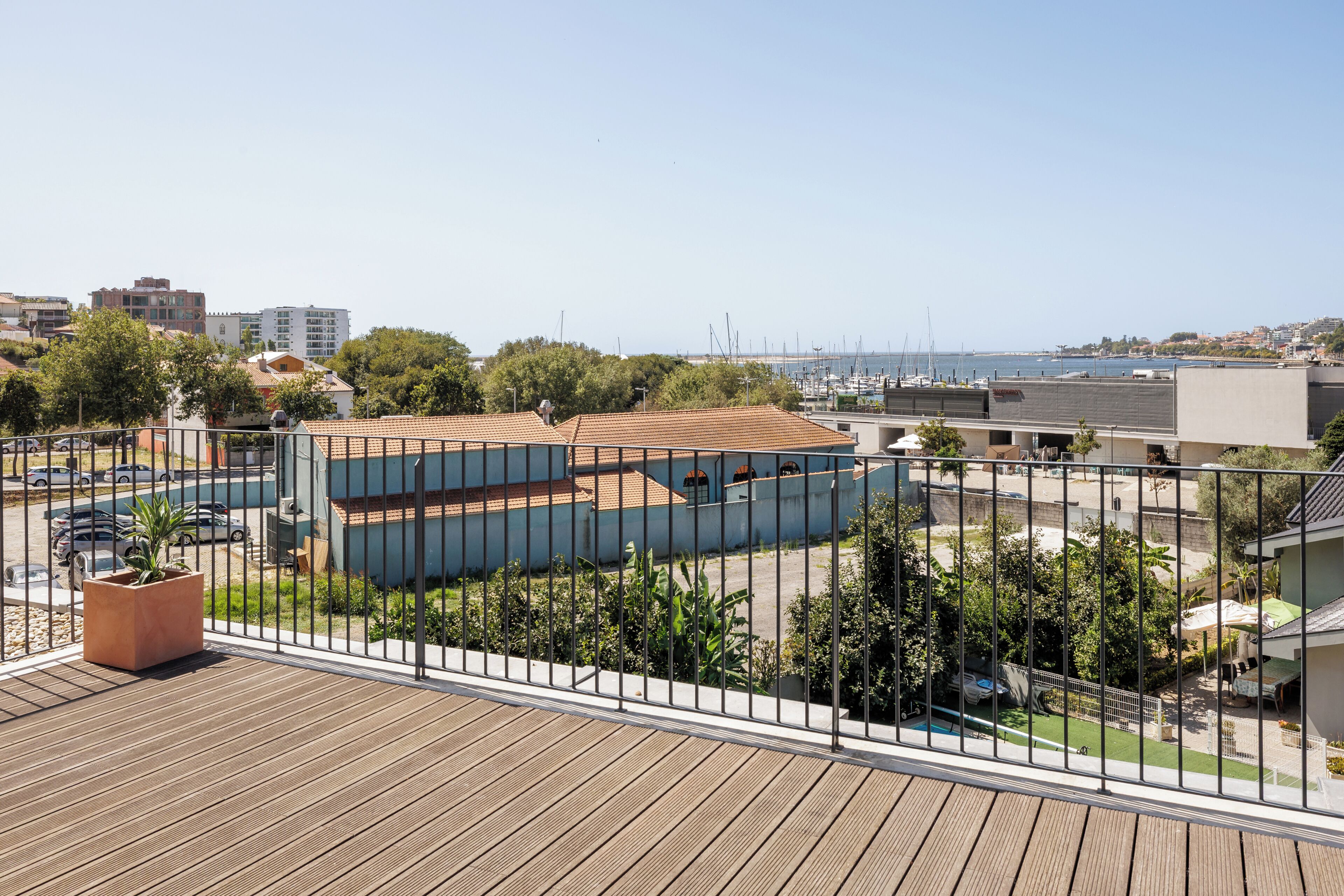 A view from a balcony overlooking a marina with boats, a parking area, and buildings in the distance.