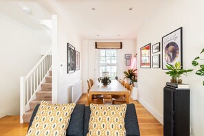 Uma sala de jantar com mesa de madeira, cadeiras e uma escada à esquerda.