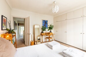 A bedroom with a bed, a desk, a chair, a wardrobe, and a mirror. - Stylish Notting Hill Home with Patio (London)