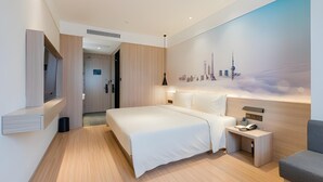 Een moderne hotelkamer met een groot bed, nachtkastje en een stadsgezicht muurschildering.