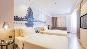 Een hotelkamer met twee bedden, een groot wanddecor, een televisie en een nachtkastje.