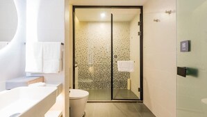 Een moderne badkamer met een glazen douchecabine, een wit bad en een toilet.