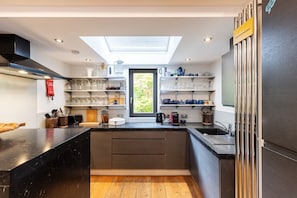A modern kitchen with a skylight, black countertops, and built-in shelves. - Stunning Belsize Park Home near Hampstead (London)