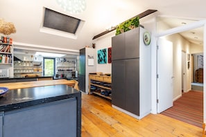 A modern kitchen with a large refrigerator, wooden flooring, and a built-in herb garden. - Stunning Belsize Park Home near Hampstead (London)