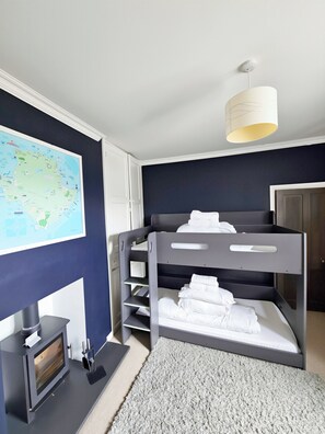 Una habitació amb un llit superposat, un mapa al mur, una llar de foc i un llum penjant.