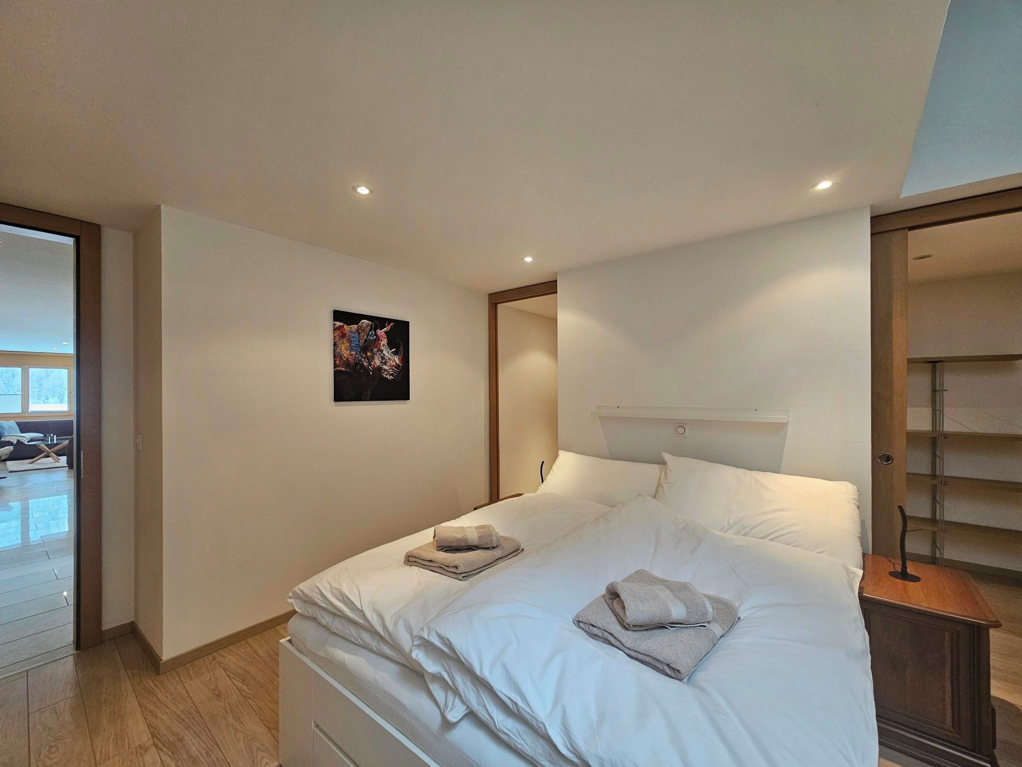 Ein Schlafzimmer mit einem Bett, einem Nachttisch, einem Wandregal und einem Gemälde.