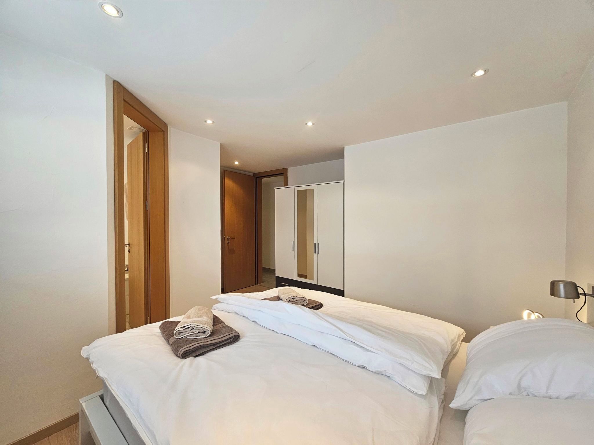 A hotel room with a bed, a wardrobe, and a mirror.