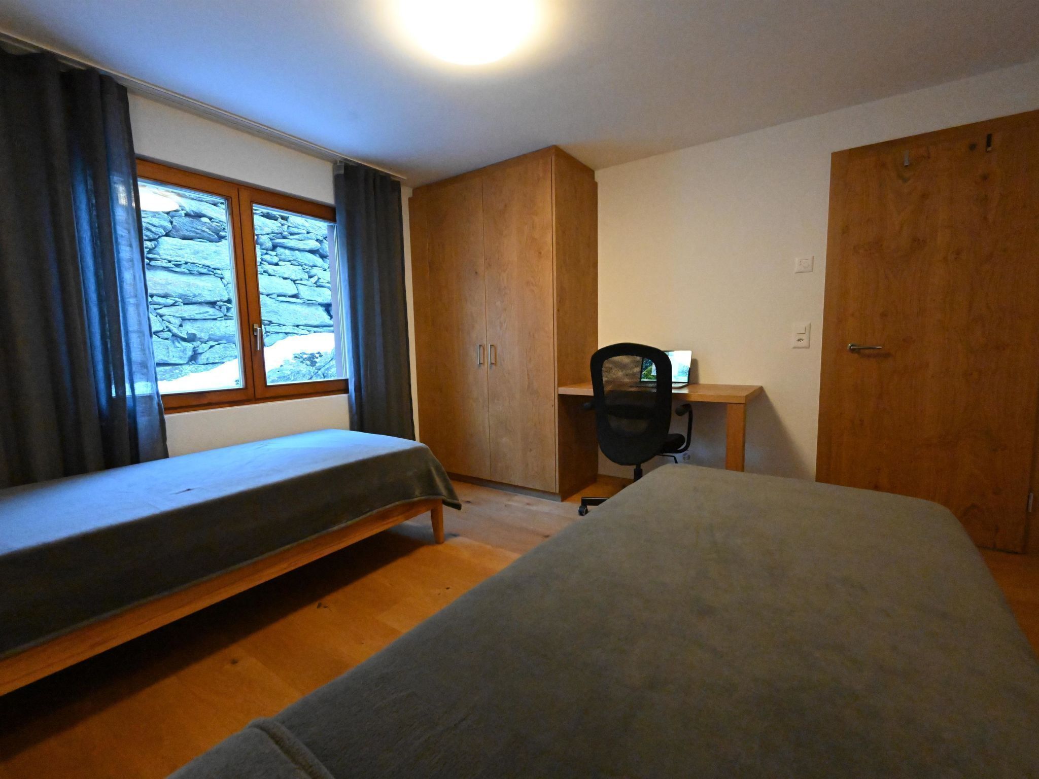 Ein Schlafzimmer mit Bett, Schreibtisch, Stuhl und Kleiderschrank.