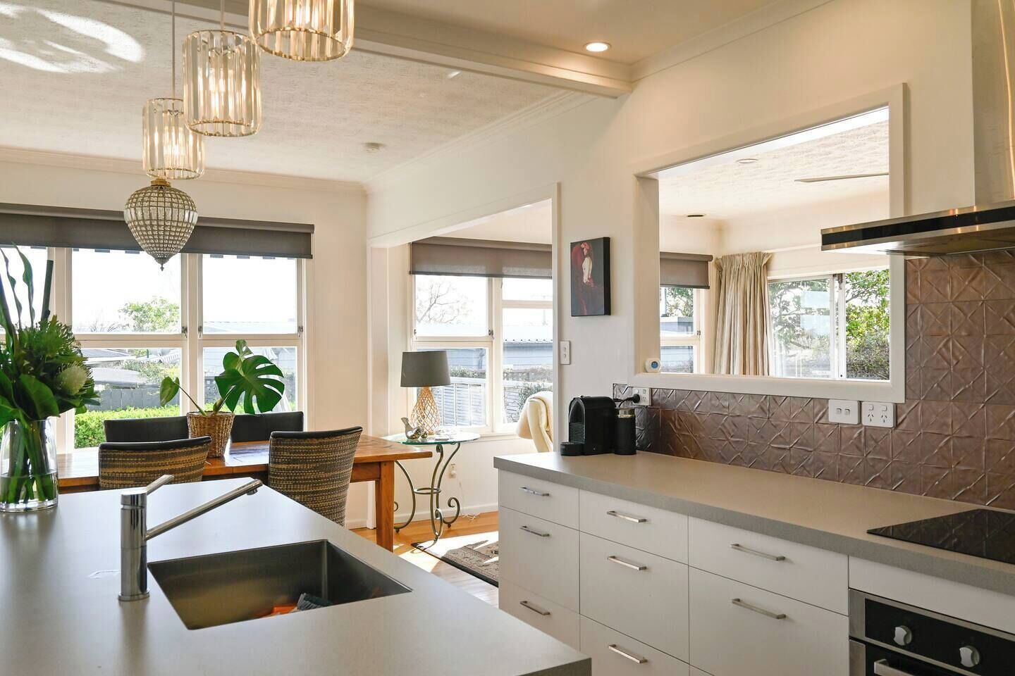 Een moderne keuken met een centraal eiland, hanglampen en uitzicht op de omgeving.
