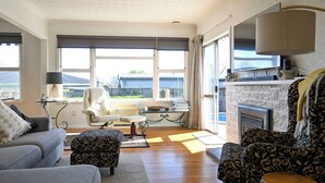A living room with a fireplace, a sofa, a chair, and a table. - Pool & Spa - Havelock North (Havelock North)