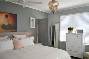 Ein Schlafzimmer mit Bett, Nachttisch, Lampe, Kommode und einem Bild an der Wand.