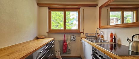 A compact kitchen with wooden countertops, a stainless steel sink, and a kettle.