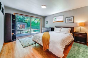 A bedroom with a bed, a nightstand, a dresser, a window with a view of greenery, and a ceiling light. - 1/2 Mi to Alki Beach + Puget Sound Views! (Seattle)