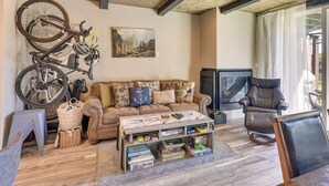 A living room with a sofa, a coffee table, a mounted bicycle, a painting, and a television. - Renovated Tahoe Keys Getaway Near Lake & Heavenly (South Lake Tahoe)
