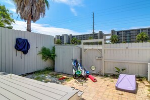 Ein Garten mit einer Holzterrasse, einem weißen Zaun und einer Palme.