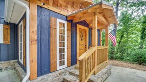 Een houten vakantiehuis met een veranda, stenen trappen en een Amerikaanse vlag.