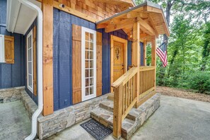 Eine Holzjagdhaus mit Veranda, Steinstufen und einer amerikanischen Flagge.