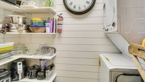 Een keuken met witte kastjes, een klok en diverse keukenapparaten.