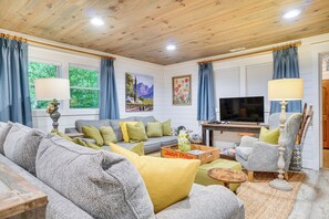 Ein gemütliches Wohnzimmer mit einer Couch, einem Fernseher und einem Gemälde an der Wand.