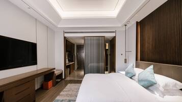 Una habitación de hotel moderna con una cama grande, un televisor de pantalla plana, un aparador de madera y un vestidor.