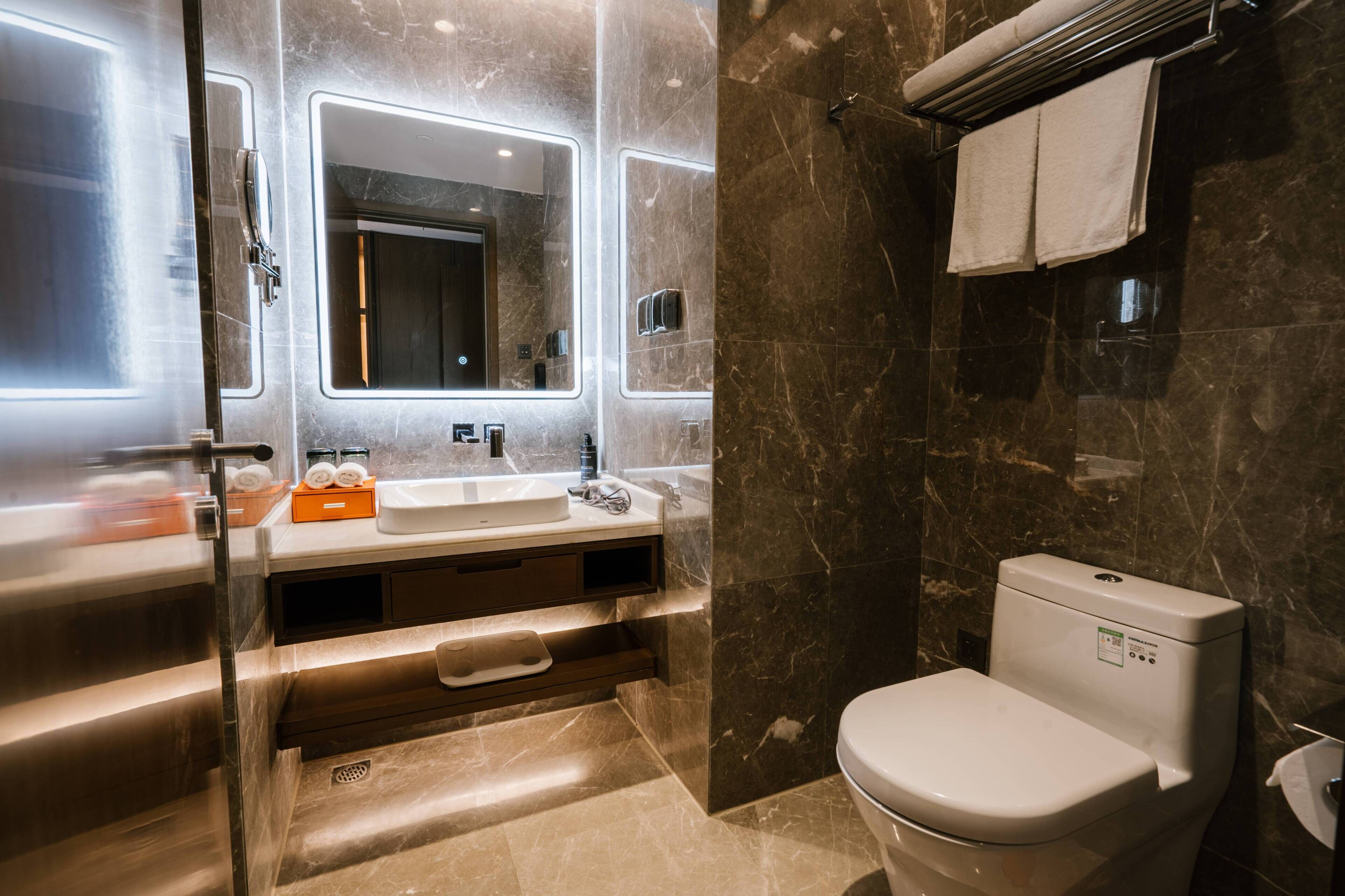 A modern bathroom with a glass-enclosed shower, a white sink, and a toilet.