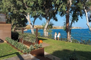 A coastal garden with a pergola, seating area, and a view of the sea. - Zurafa Resort (Syracuse)
