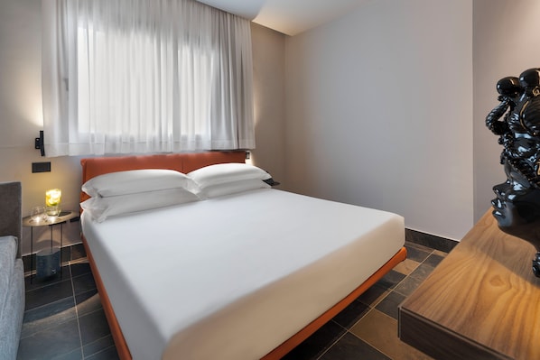 A hotel room with a bed, a nightstand, a lamp, and a decorative sculpture. - Zurafa Resort (Syracuse)
