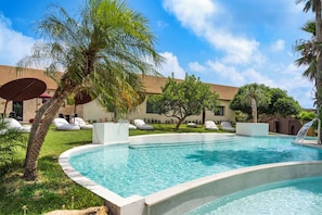 A swimming pool with lounge chairs and palm trees. - Zurafa Resort (Syracuse)