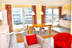 Eine moderne Wohnung mit Essbereich, Küche und großen Fenstern.