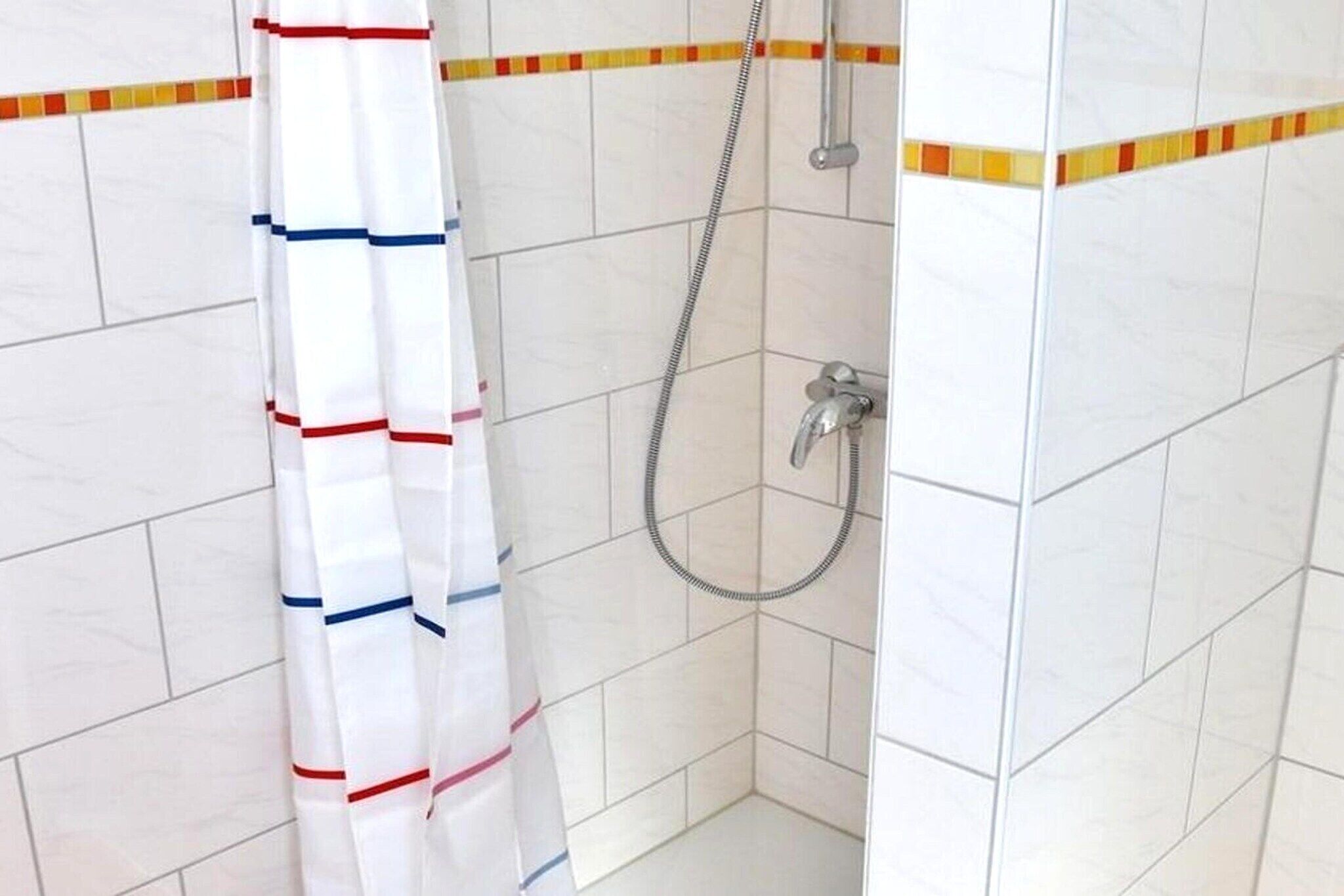 A shower area with a showerhead and a curtain.