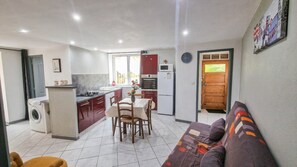 A compact living space with a kitchenette, dining area, and a sofa. - Charming 1-Bedroom Apartment - Private Pool & Yard - Quiet 24/7 (Graissessac)