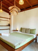 A bedroom with a wooden bed frame, a green-striped bedspread, and a woven rattan headboard.
