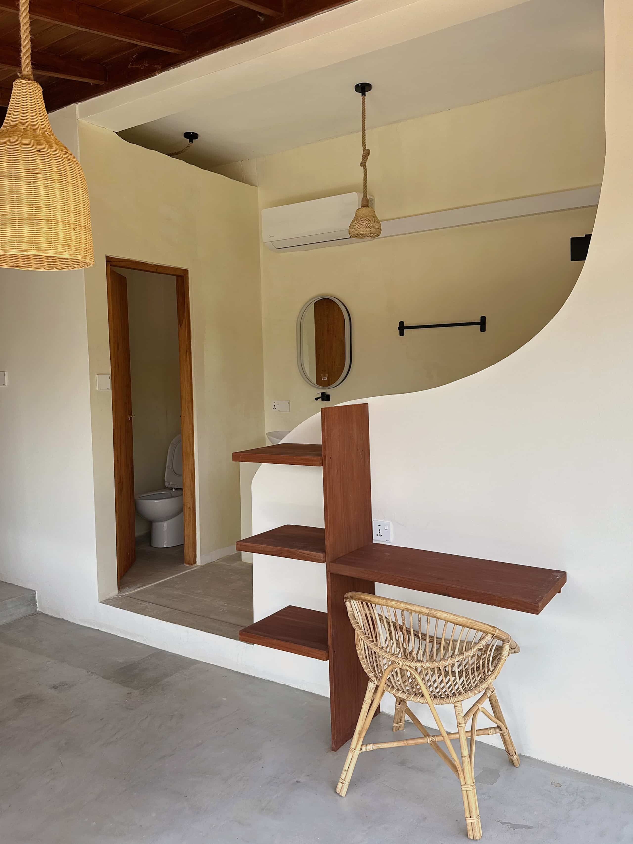 A modern interior with a wooden staircase, a wicker chair, and a hanging light fixture.