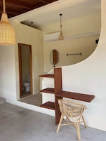 Un interior moderno con una escalera de madera, un sillón de mimbre y una lámpara colgante.