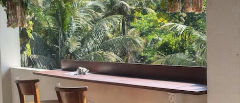 A wooden bar with two stools and hanging plants.