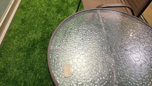 A balcony with artificial grass, a glass table, and two wicker chairs. - شقة فخمة في برج الجوهرة داماك (Jeddah)